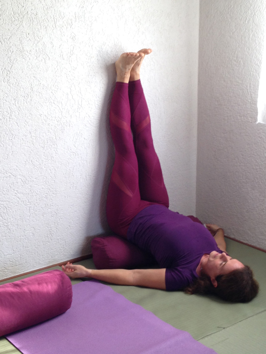 Yoga Übungsleiterin Annette Kunkel macht einen Halben Schulterstand mit Beinen an der Wand.